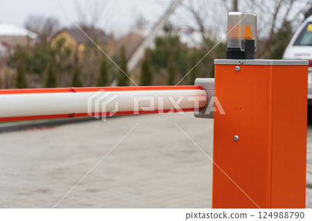 A security barrier stands at the entrance of a parking lot, ensuring controlled access to vehicles in a suburban neighborhood on a cloudy day A security barrier stands at the entrance of a parking lot, ensuring controlled access to vehicles in a suburban neighborhood on a cloudy day 124988790