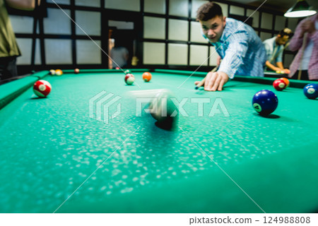 Young man trying to hit the ball in billiard. Young man trying to hit the ball in billiard. 124988808
