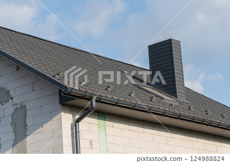 Newly constructed home featuring a gray roof and chimney against a clear sky, showcasing modern architecture and design elements Newly constructed home featuring a gray roof and chimney against a clear sky, showcasing modern architecture and design elements 124988824