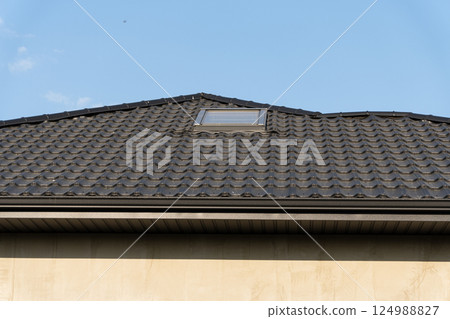 A residential building with a distinct rooftop design hosts a skylight, illuminated by the bright blue sky above 124988827