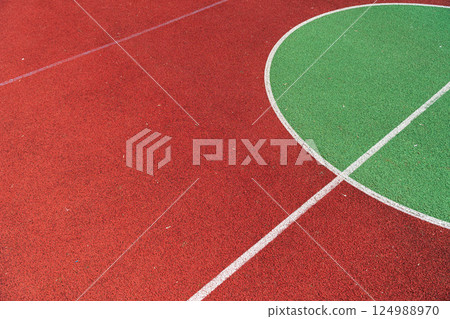 Vibrant basketball court featuring a red surface and a green half-court area, perfect for sports activities and community events Vibrant basketball court featuring a red surface and a green half-court area, perfect for sports activities and community events 124988970