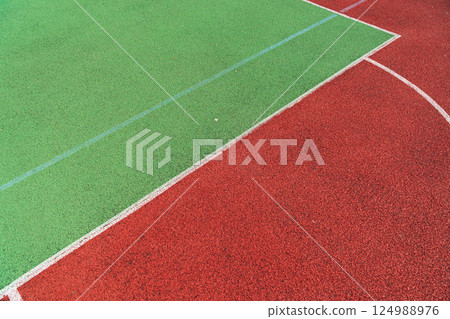 A vibrant sports court featuring distinct green and red sections ideal for basketball, tennis, and other outdoor games 124988976