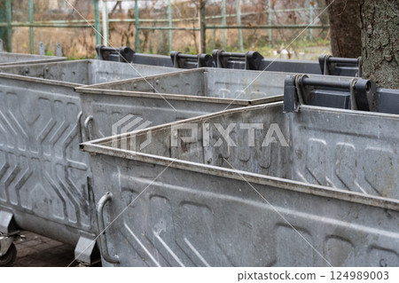 Metal containers stand empty and unused in a recycling area, capturing the quiet moment in an urban landscape on an overcast day 124989003