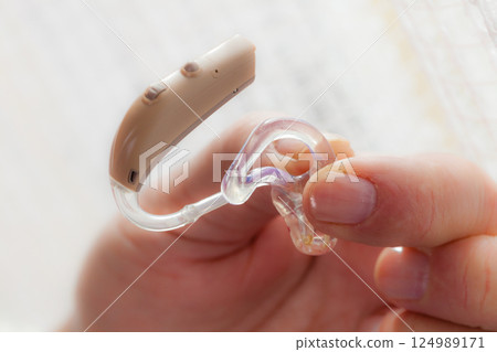 senior person holding hearing aid closeup 124989171
