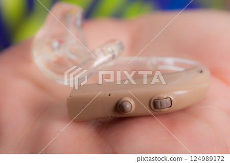 senior person holding hearing aid closeup 124989172