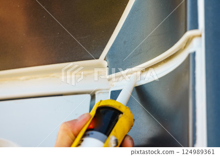 Applying silicon on caravan body 124989361
