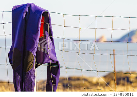 Diving suis drying on fence with sea view 124990011