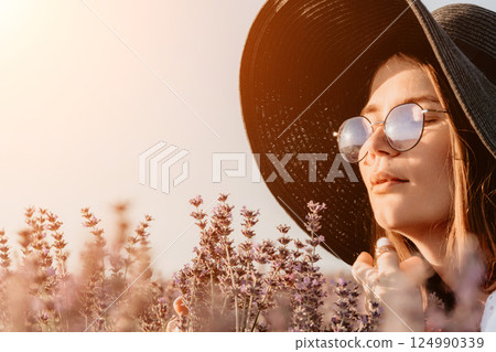 Woman in a Wide-Brimmed Hat Smelling Lavender 124990339