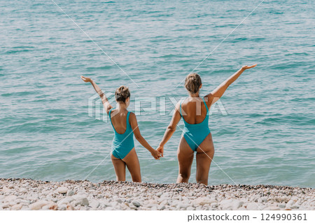Two Women in Blue Bathing Suits on a Pebble Beach 124990361