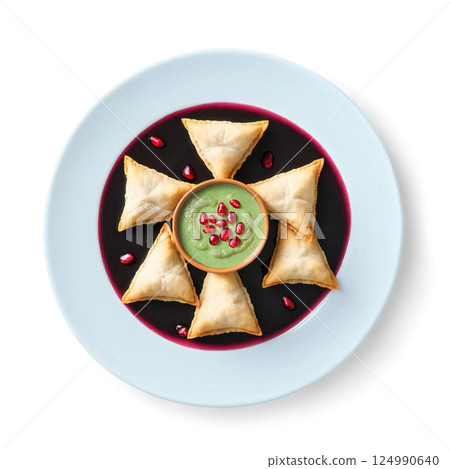 Samosa Chaat - Crushed golden samosas topped with tangy tamarind sauce, spicy mint chutney, yogurt, sev, and pomegranate seeds. 124990640