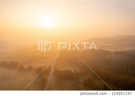Aerial image with multicolored forest and a road on a foggy morning of autumn 124991197