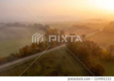 Drone aerial image with multicolored forest and a road on a foggy morning of autumn 124991212