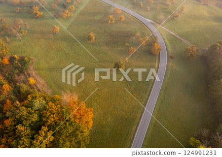Winding road through autumn nature at sunrise, drone aerial view 124991231
