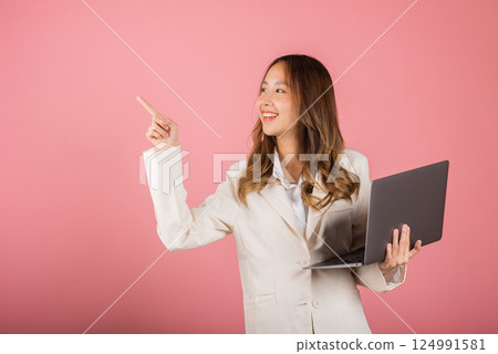 Portrait business woman holding laptop point finger empty space studio shot isolated on pink background, Young smiling happy fun attractive cheerful skilled female hold computer with copy space Portrait business woman holding laptop point finger empty space studio shot isolated on pink background, Young smiling happy fun attractive cheerful skilled female hold computer with copy space 124991581