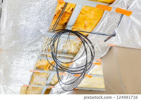 Electrical wiring and insulation being installed in building construction project 124991716
