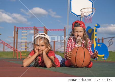 Girls on the city playground relax after playing basketball Girls on the city playground relax after playing basketball 124992139