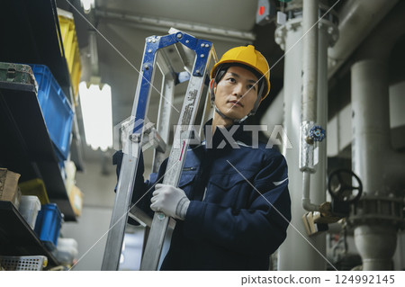 Worker carrying a stepladder 124992145