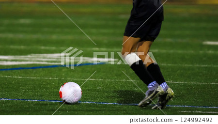Player Dribbles Soccer Ball on Field During Evening Match 124992492