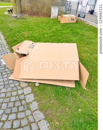 Discarded cardboard boxes lying on grass near sidewalk in urban outdoor area. High quality photo 124992521