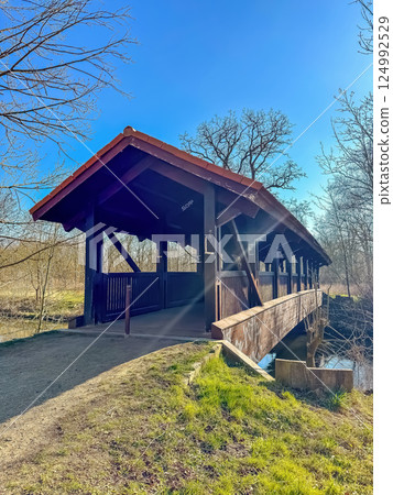 Wooden covered footbridge in nature park on sunny day with clear blue sky. High quality photo 124992529