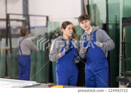 Woman and guy employees in workshop discuss work processes Woman and guy employees in workshop discuss work processes 124992532