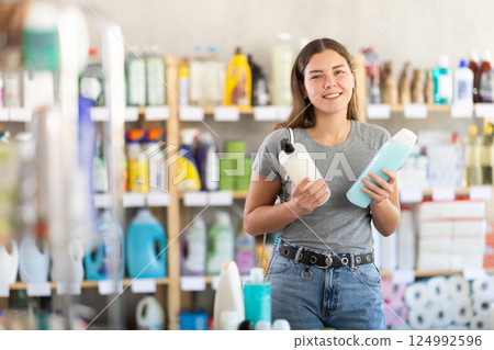 Young woman choosing shampoo or shower gel in store 124992596