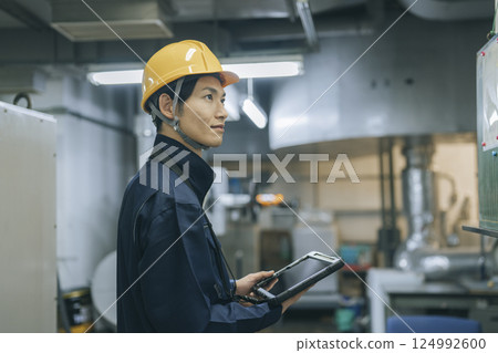 一名 30 多歲的男子身穿工作服,手裡拿著一台平板電腦 一名 30 多歲的男子身穿工作服,手裡拿著一台平板電腦 124992600