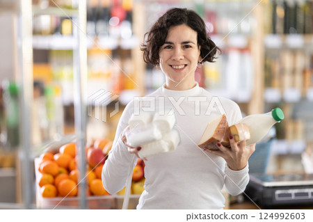 Woman picked up lot of varied food, and with armful of groceries, they choose something else 124992603