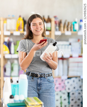 Young woman scanning qr code for shampoo or shower gel Young woman scanning qr code for shampoo or shower gel 124992625