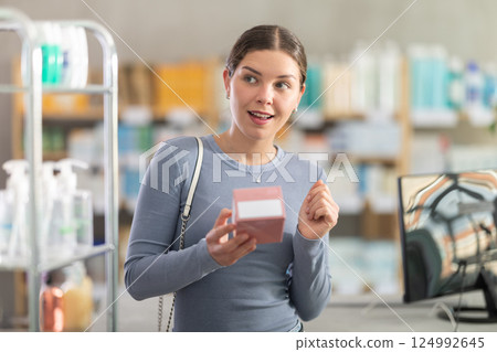Young girl customer choosing pills in box in drugstore Young girl customer choosing pills in box in drugstore 124992645