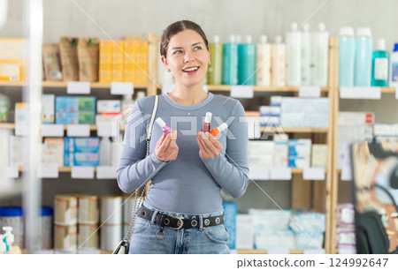 Young woman choosing nail polish in drugstore Young woman choosing nail polish in drugstore 124992647