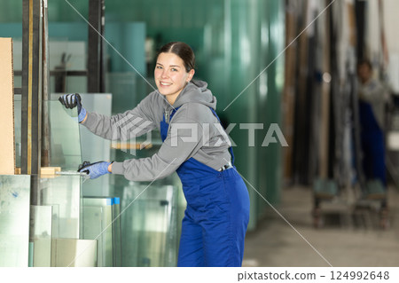 Young woman stacking glass sheets in factory Young woman stacking glass sheets in factory 124992648
