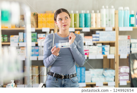 Young girl customer choosing ointment in box in drugstore 124992654