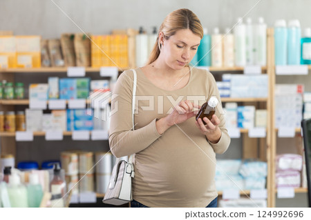 Pregnant woman choose cough syrup in pharmacy 124992696
