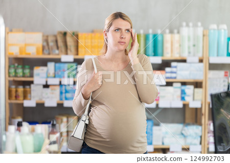 Pregnant woman having headache in drugstore Pregnant woman having headache in drugstore 124992703