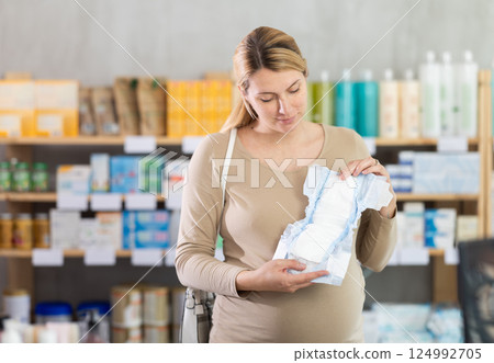Pregnant woman in drugstore chooses diapers for newborn Pregnant woman in drugstore chooses diapers for newborn 124992705