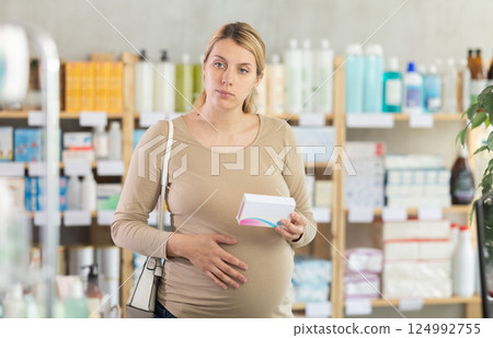 Pregnant woman chooses pills at pharmacy Pregnant woman chooses pills at pharmacy 124992755