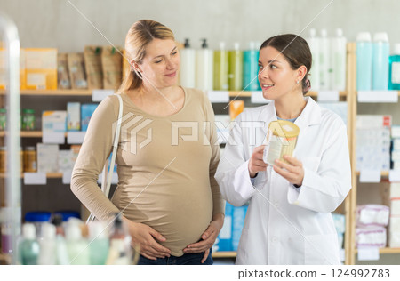 Smiling pharmacist offering newborn formula to expecting mother 124992783