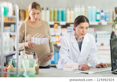 Pharmacist looking for prescription on computer for pregnant woman Pharmacist looking for prescription on computer for pregnant woman 124992924