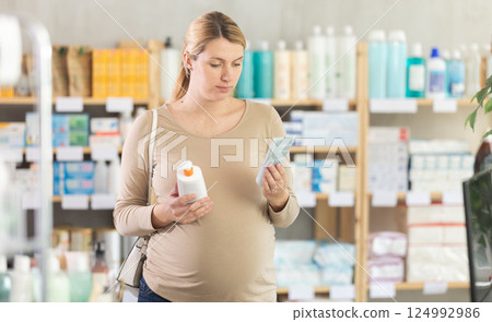 Pregnant woman chooses diaper rash cream in pharmacy 124992986