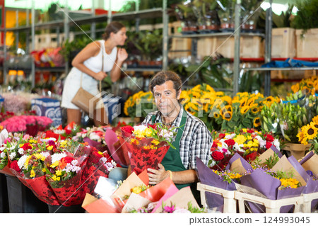 Adult male seller holding bouquet of flowers 124993045
