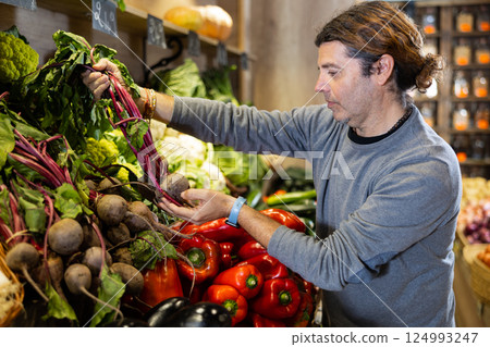 Adult man buyer chooses beets in shop 124993247