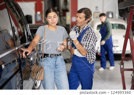 Male mechanic consulting female client on car door 124993360