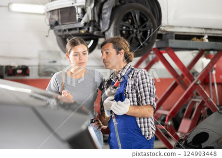 Male car repair shop worker consulting female client 124993448