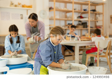 Girl working at a potter's wheel with clay 124993498