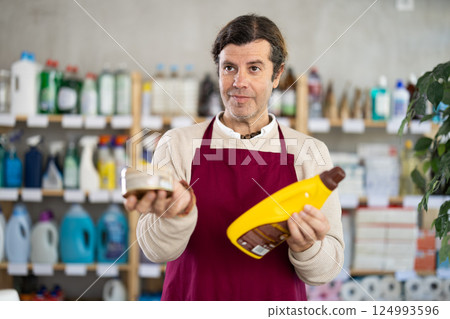 Male salesman offers to buy product for cleaning parquet or laminate 124993596