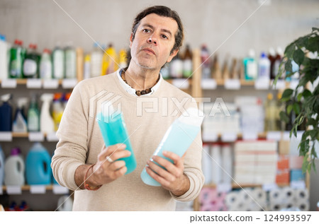 Adult man choosing shampoo or shower gel in store Adult man choosing shampoo or shower gel in store 124993597
