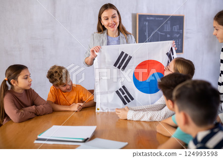 Teacher showing flag of South Korea to group of schoolchildren Teacher showing flag of South Korea to group of schoolchildren 124993598
