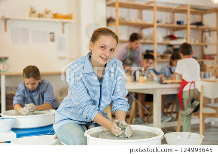 Positive teenage girl working at potter's wheel 124993645