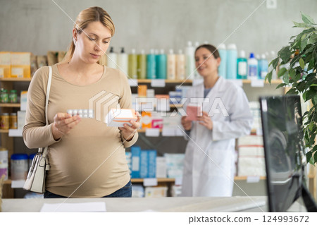 Pregnant woman choosing pills with help of pharmacist 124993672